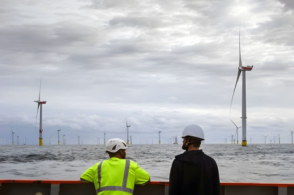 Engineers inspecting an offshore wind farm with multiple wind turbines at sea, during a technical assessment from a vessel.